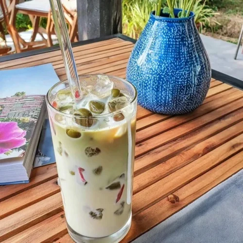 Coconut Iced Matcha Latte em um copo com gelo e coco fresco decorativo