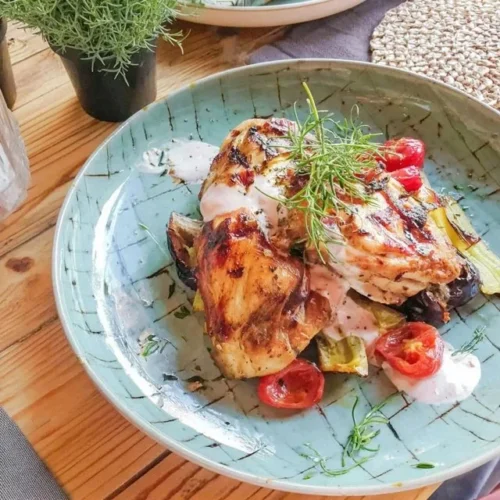 Frango grelhado infusionado com ervas e legumes coloridos, prato saboroso e saudável.