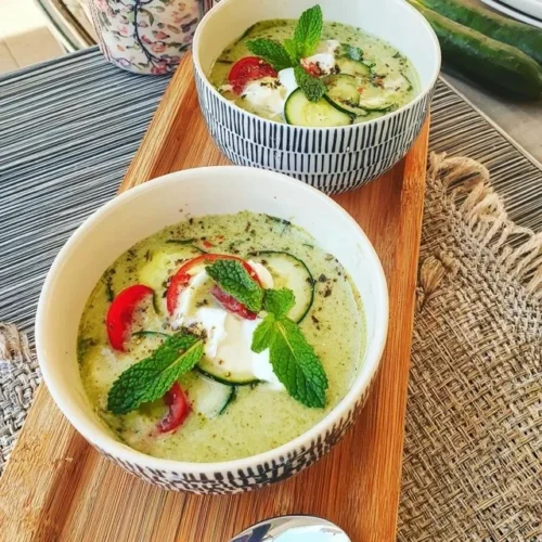 Gazpacho refrescante de pepino e hortelã em um prato decorado.