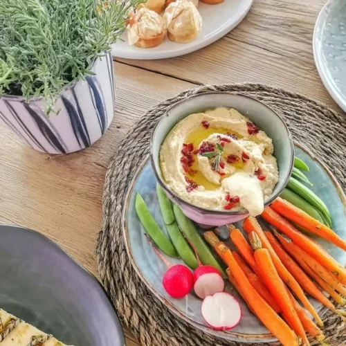 Hummus de cenoura com ervilhas doces servido em uma tigela colorida.